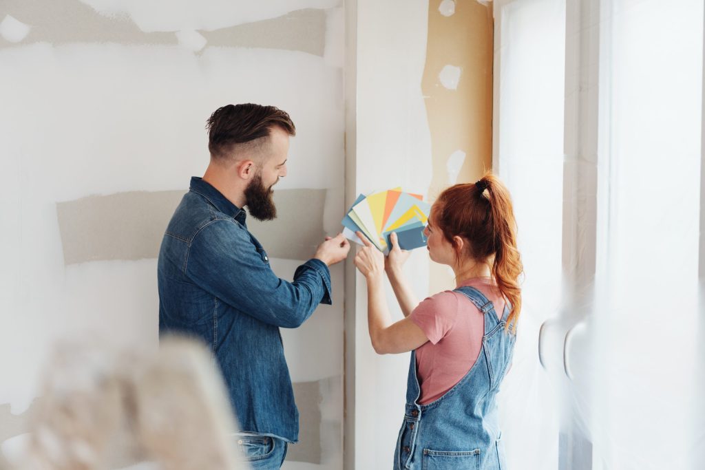 Man and woman testing paint swatches against a wall