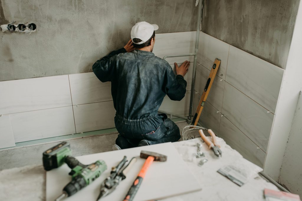 Construction worker placing tile within a room.